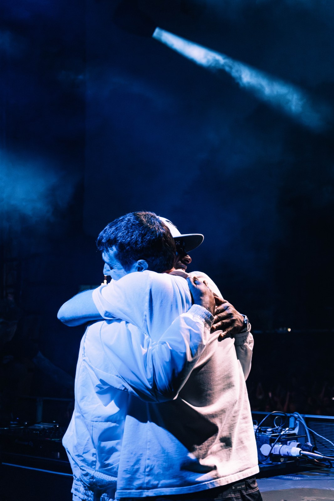 Two people embracing on stage under blue light.
