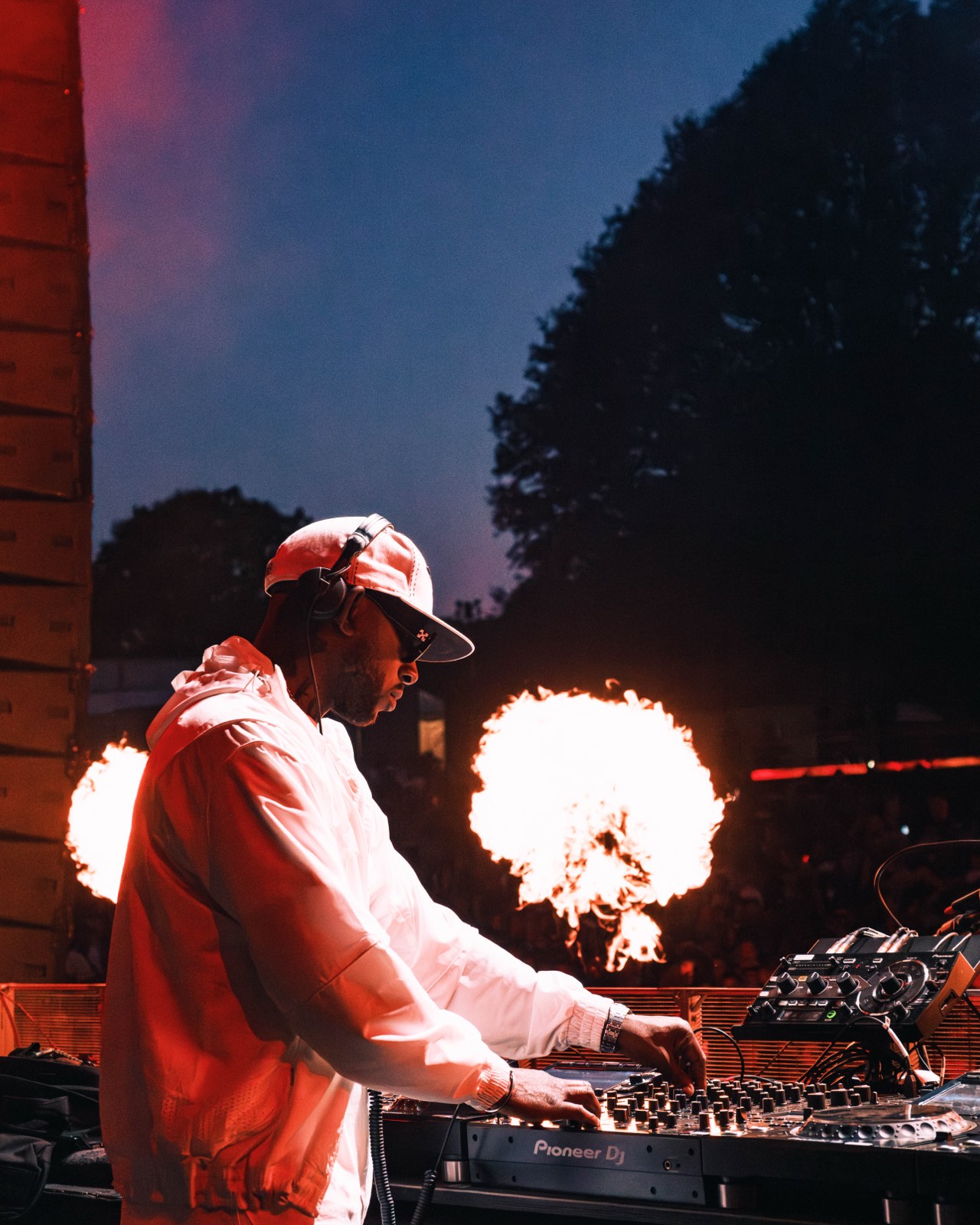 DJ performing as flames rise behind the stage.