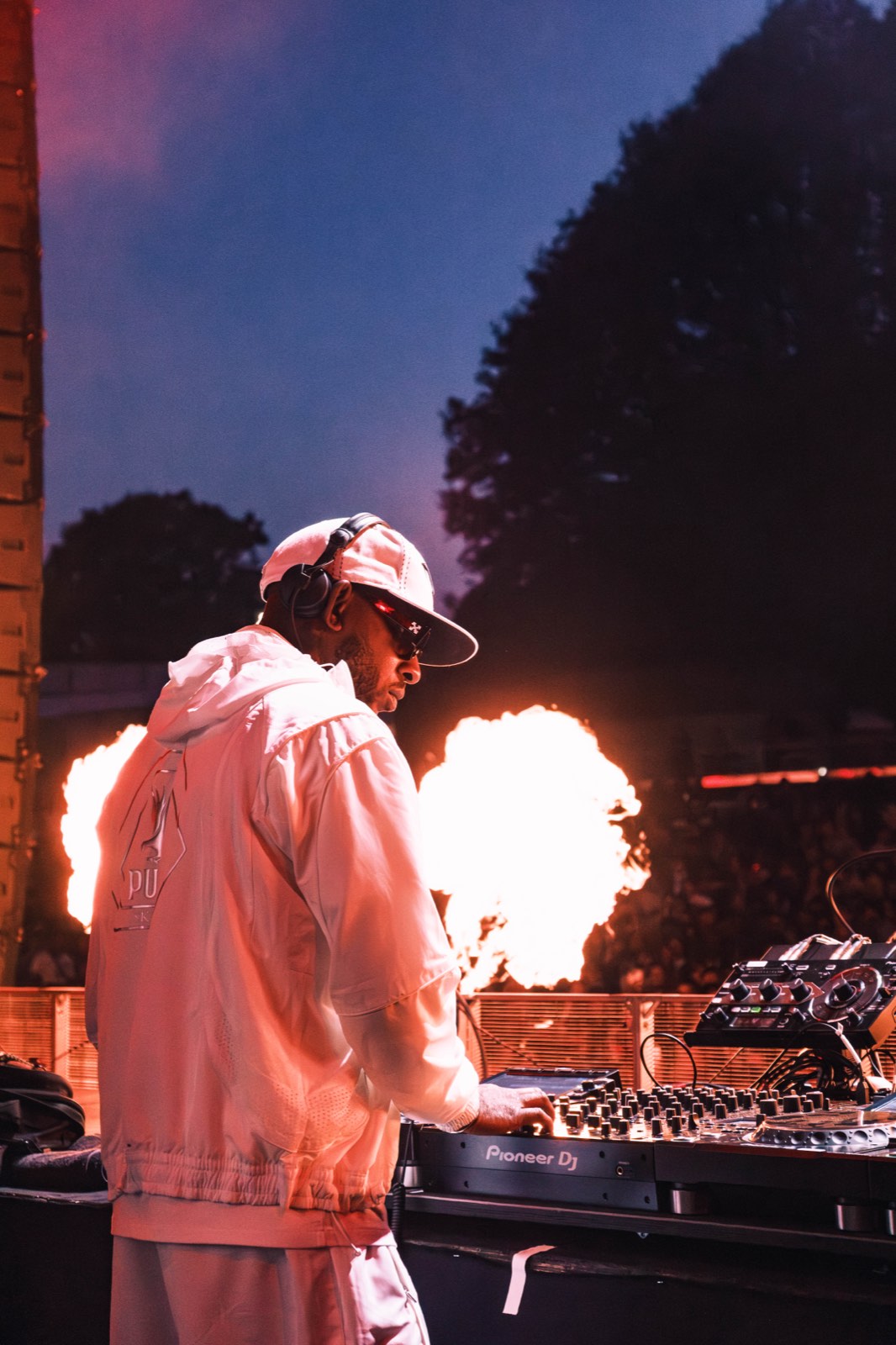 DJ performing at the decks during the finale, with flames lighting the stage.