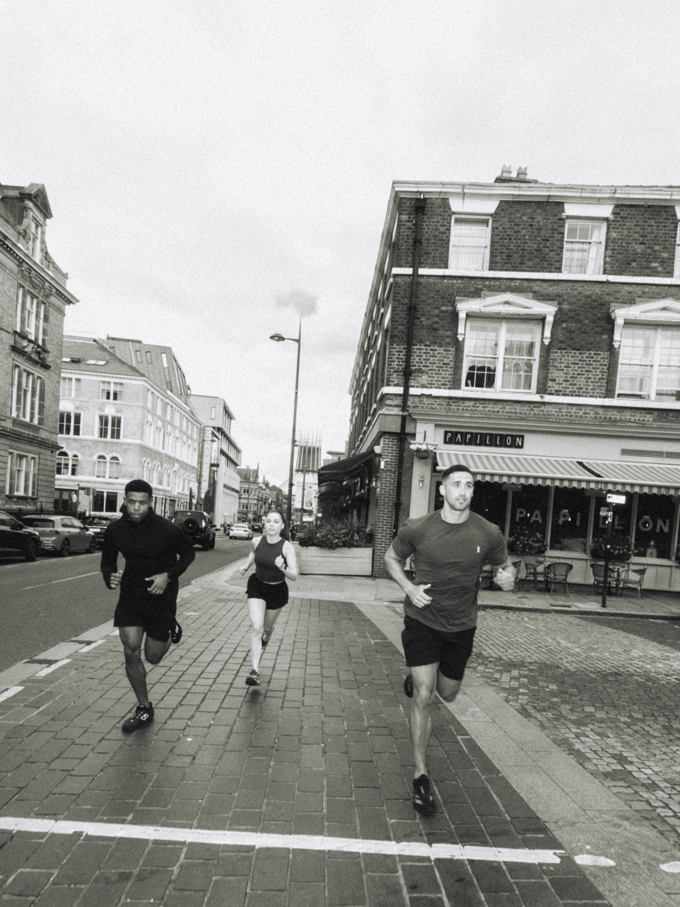 Three runners moving through the city in black and white