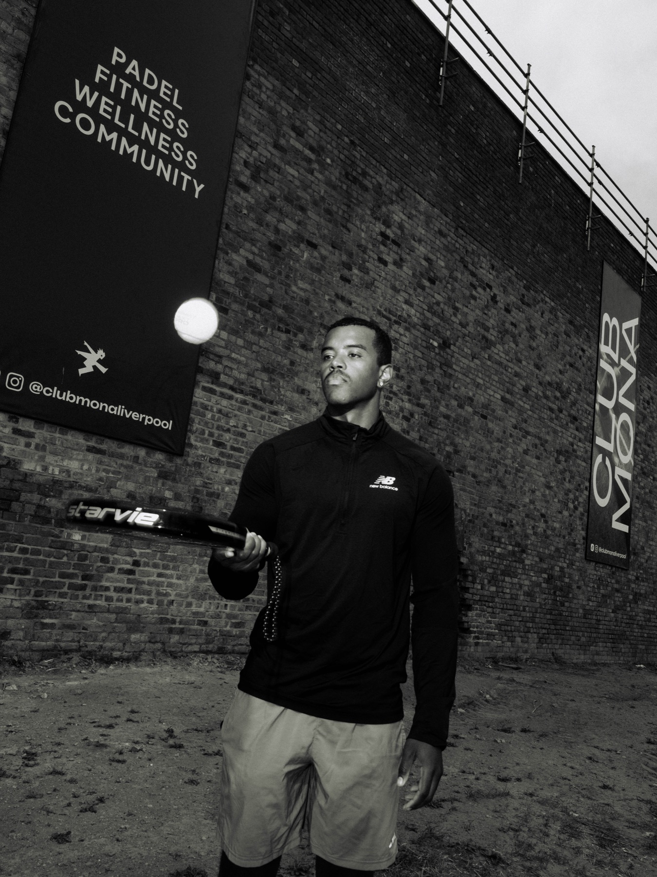 Padel player serving beneath Club Mona campaign artwork