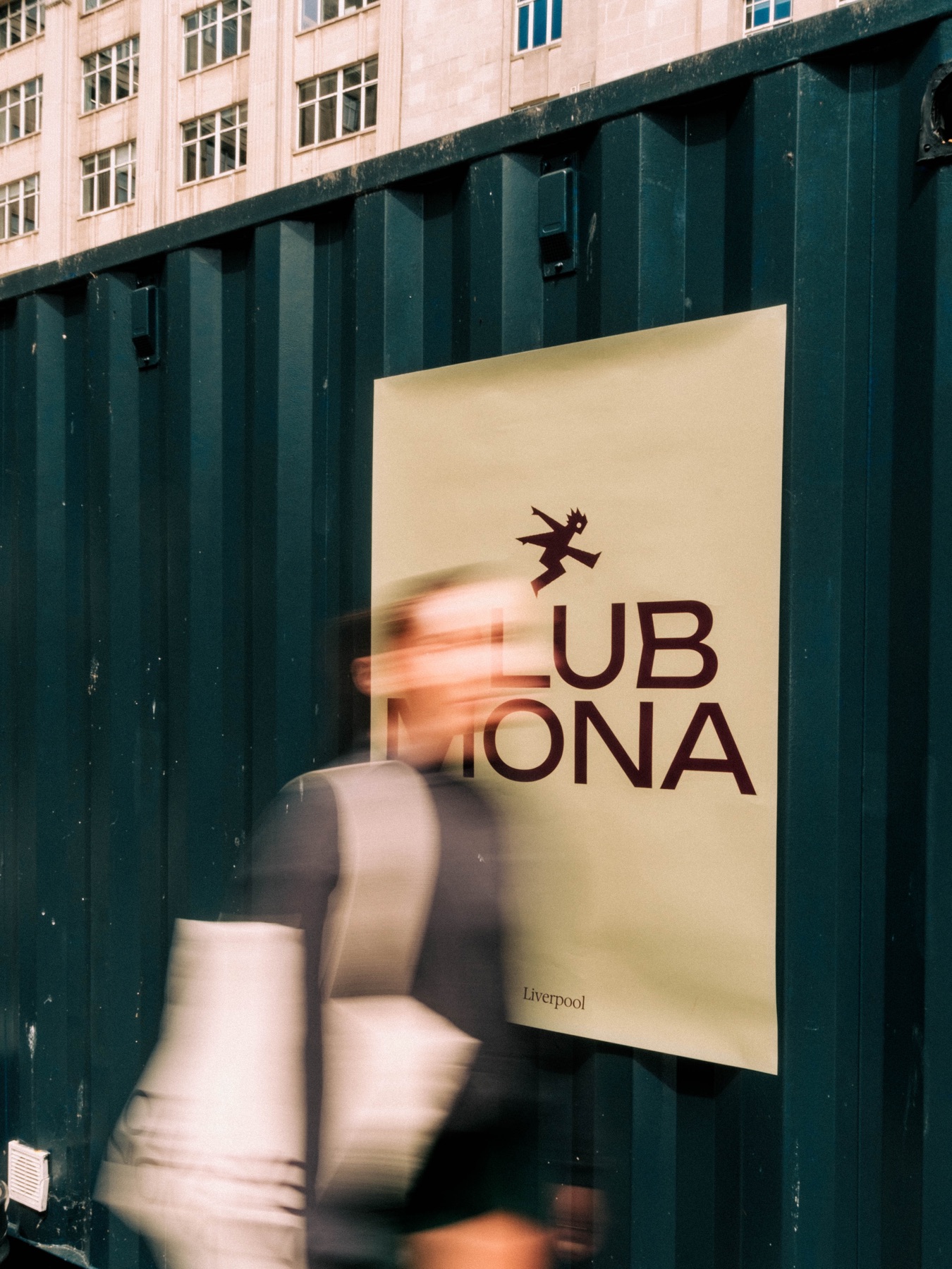 A person walking past a Club Mona street poster