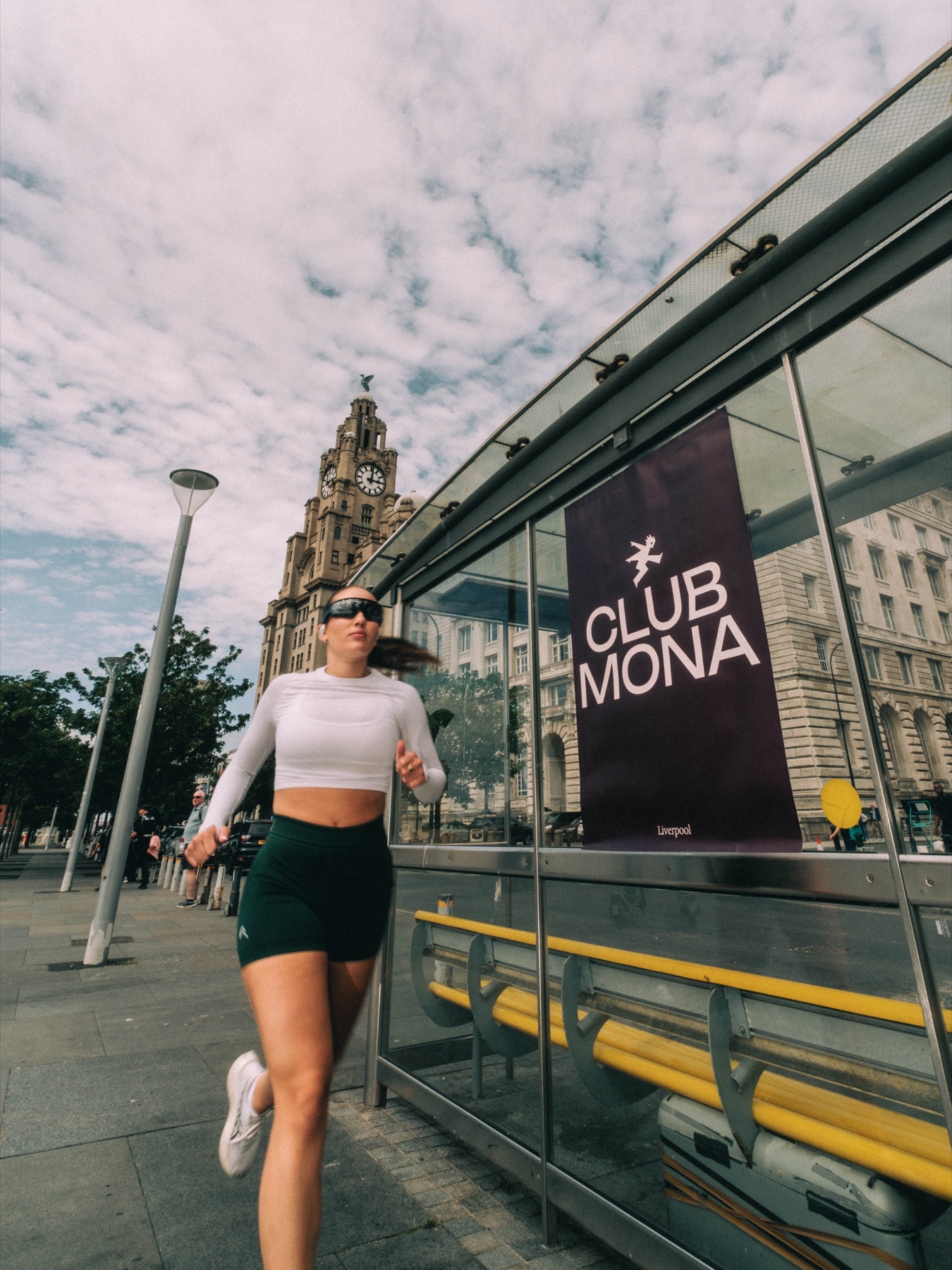 Runner passing a Club Mona poster at a bus shelter