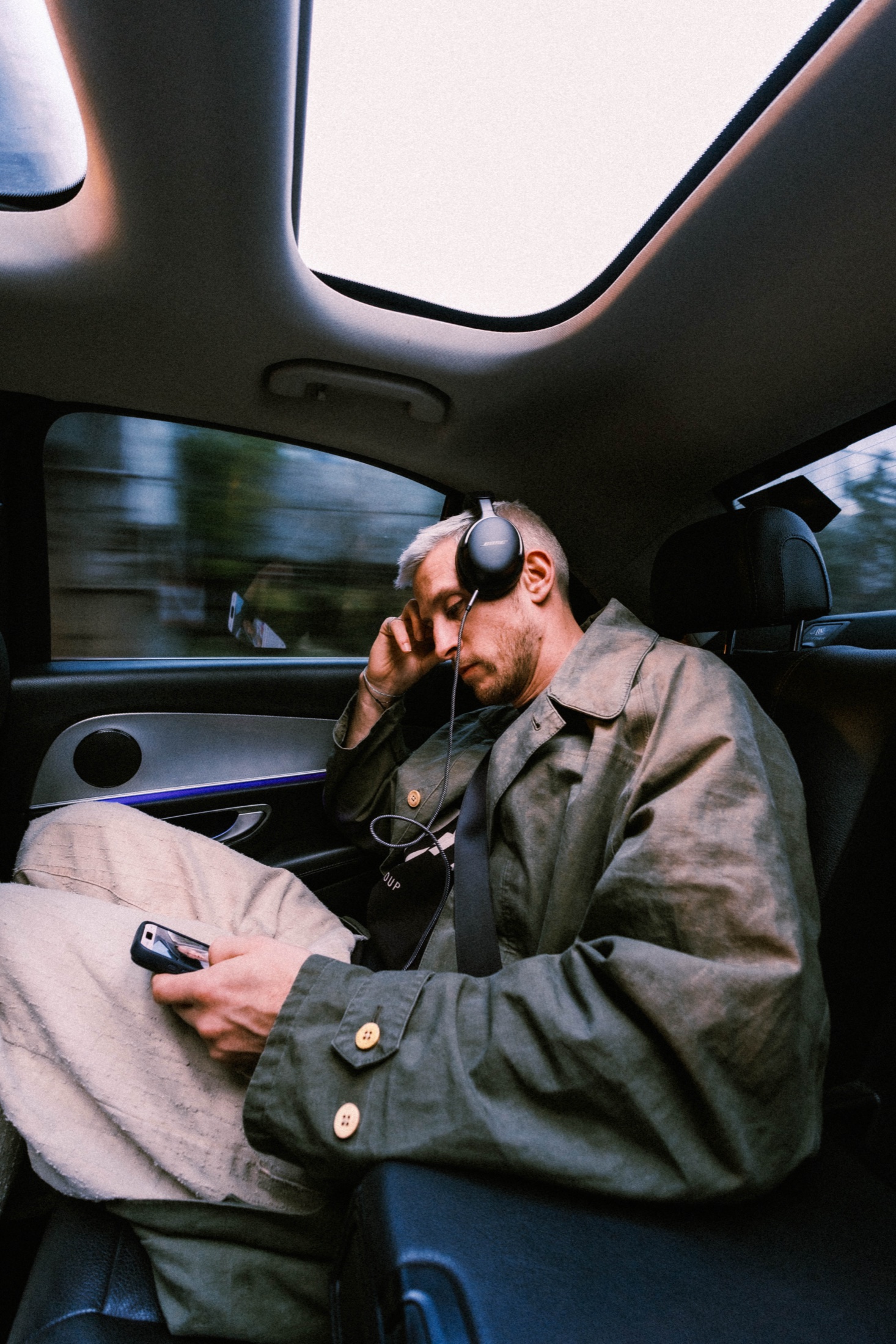Eli Brown listening to headphones in the back seat of a car.