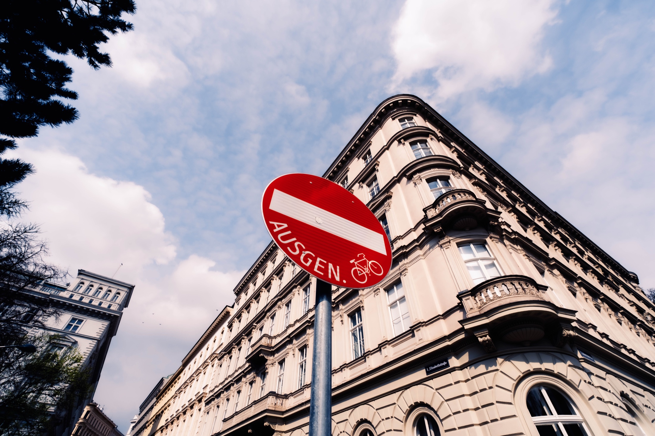 A red bicycle exit sign framed against city architecture.