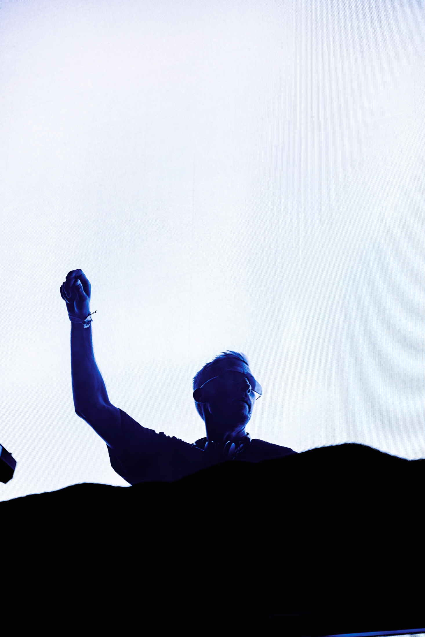 Eli Brown raising his fist in silhouette against a bright stage screen.