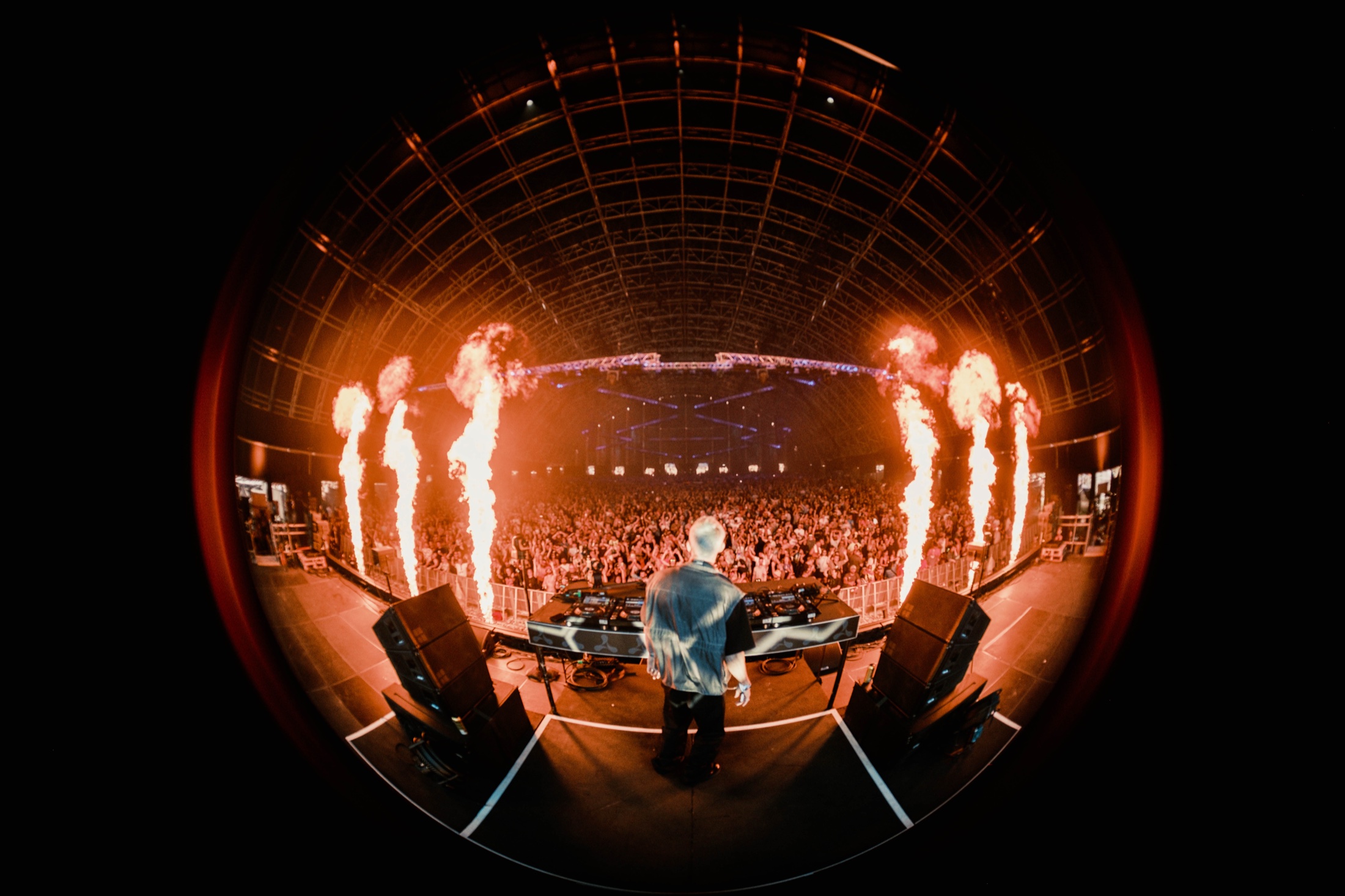 Eli Brown facing an arena crowd as flames rise beside the stage.