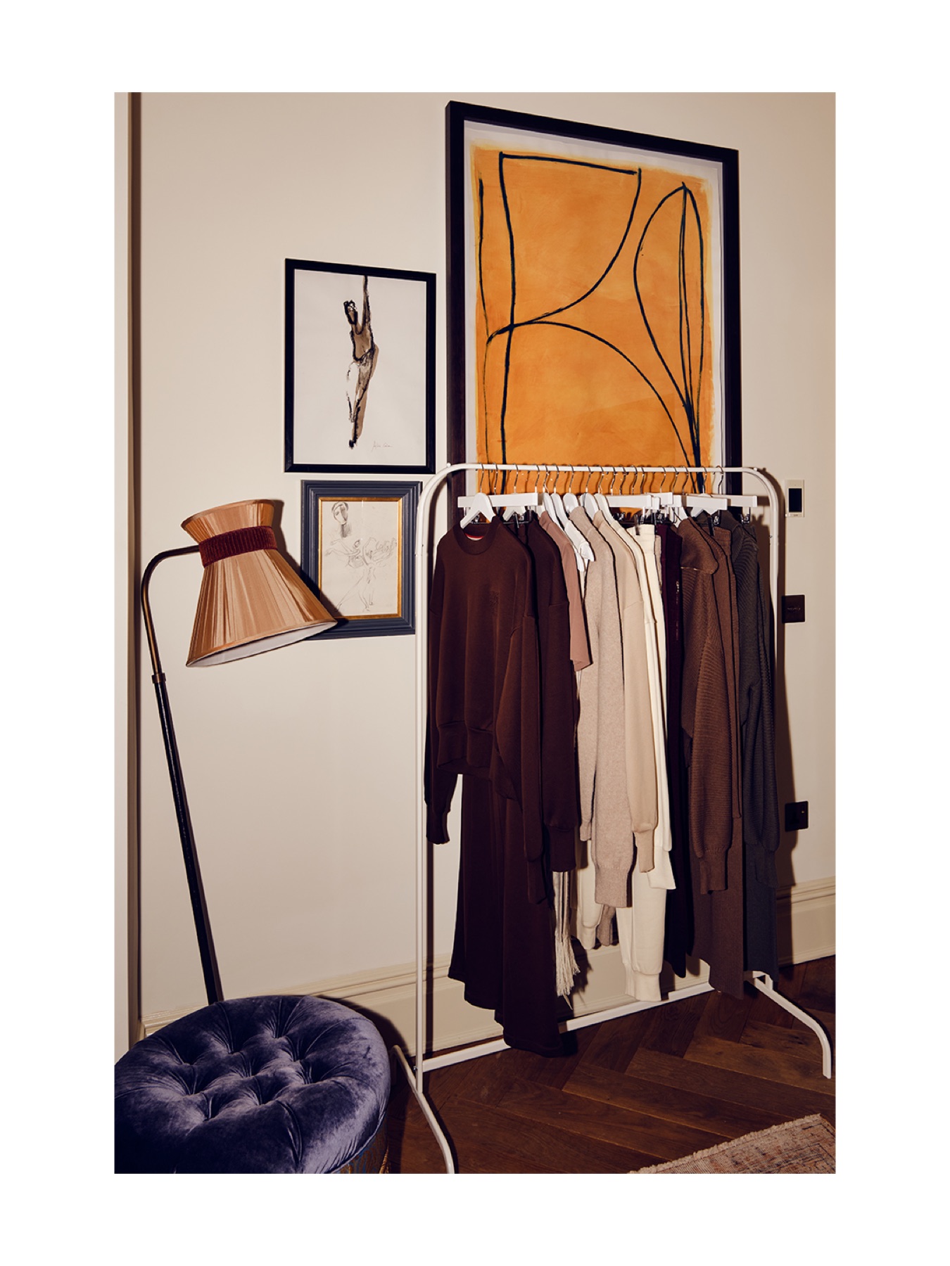 Neutral Emello garments displayed beside artwork and a sculptural lamp