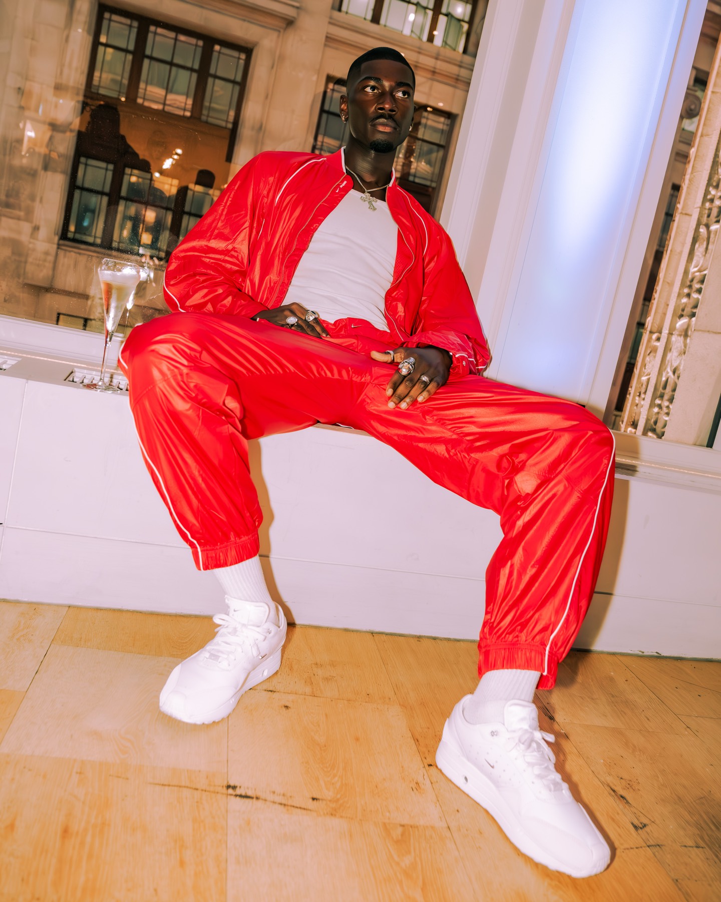 Guest in a red tracksuit photographed beside the window.