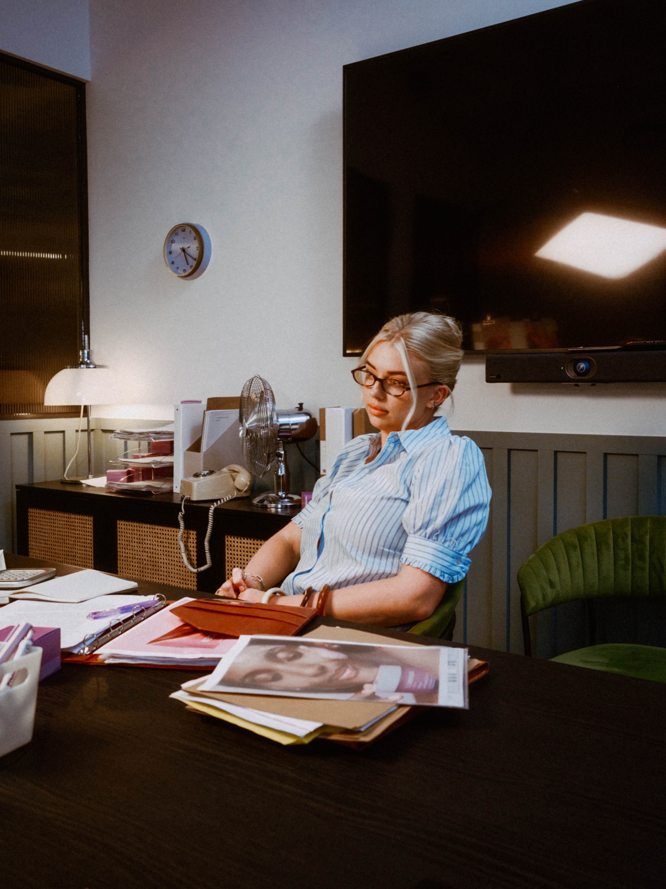 Campaign talent with glasses seated beside a desk fan
