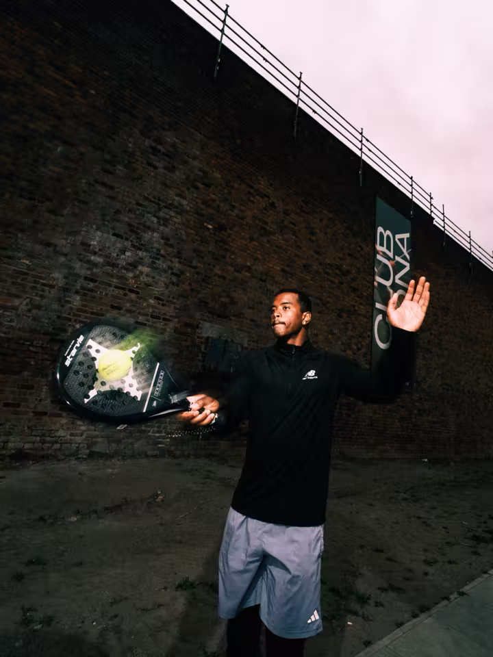 Padel player striking a ball beneath Club Mona campaign artwork