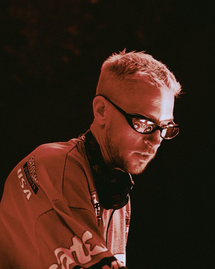 Eli Brown photographed in red stage light with sunglasses and headphones