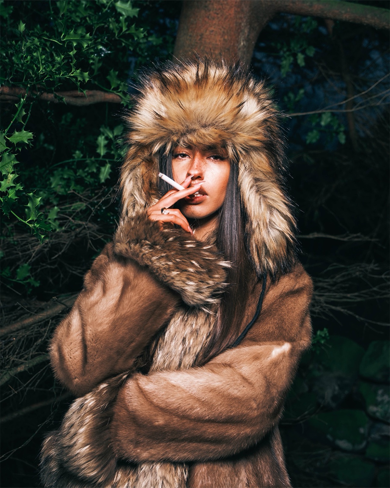 Fashion portrait with fur trim among dark woodland foliage.