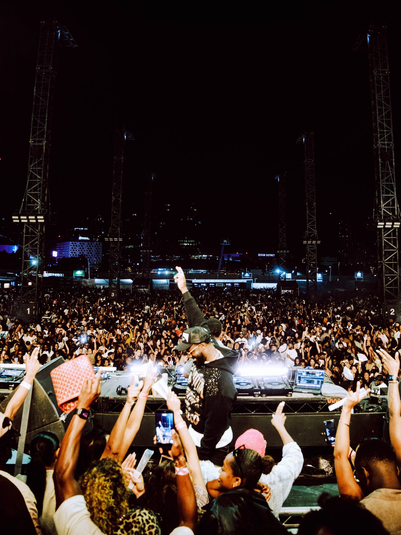Dense crowd raising phones and hands during the performance at night.