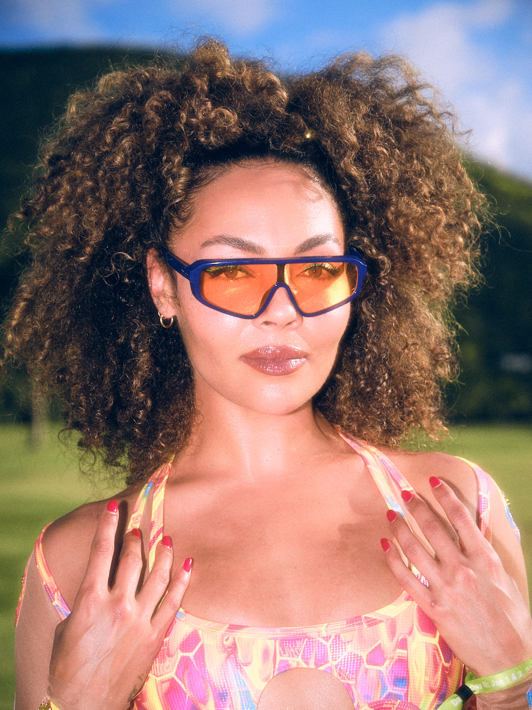 Ashley Everett in orange sunglasses, photographed against the Saint Kitts hillside